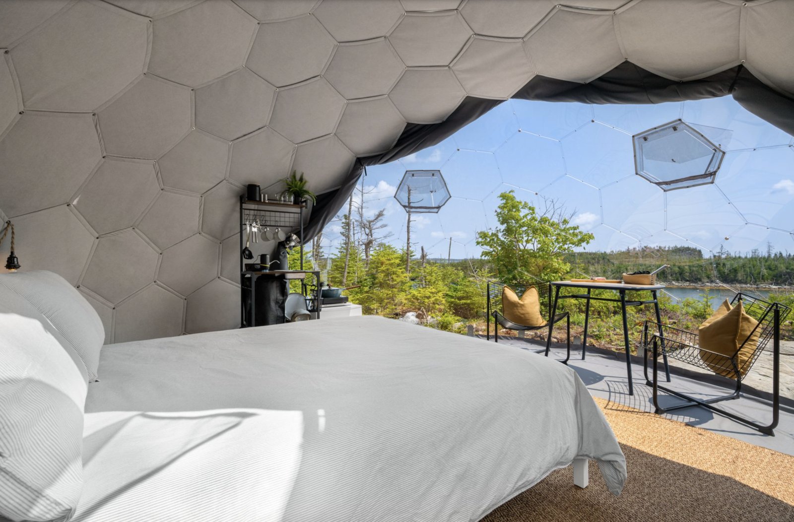 Interior of a grey geodesic glamping dome with a bed and lake view