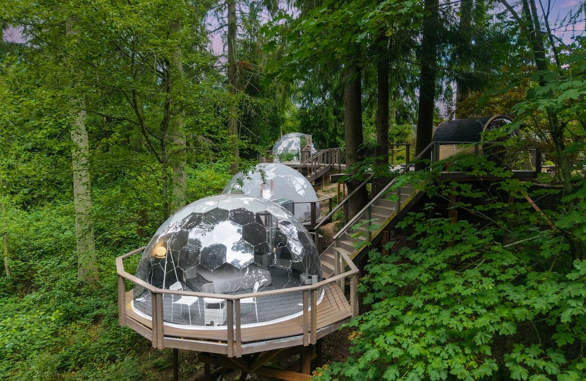 Aerial view of a mirror glamping dome on a raised forest deck