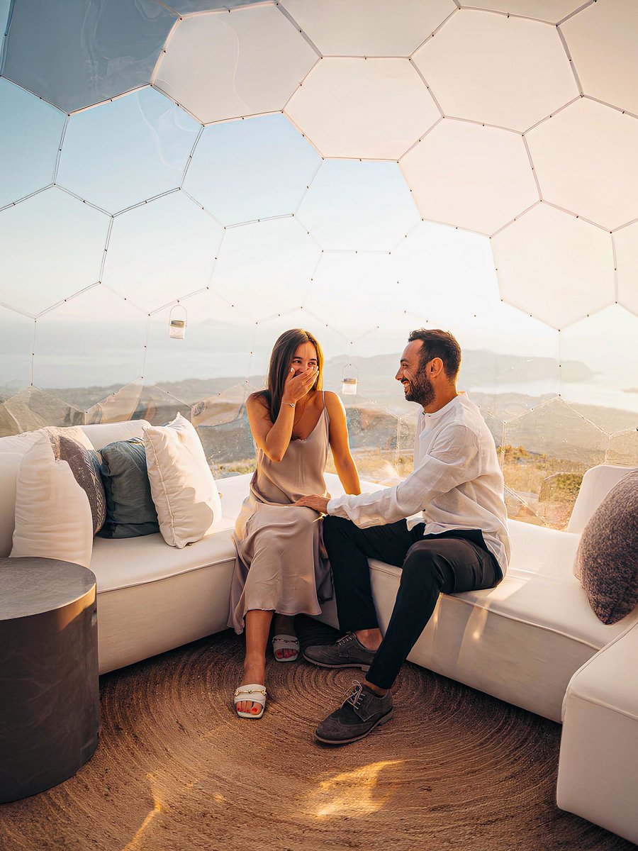 Couple in geodome lounge with ocean panorama at sunset