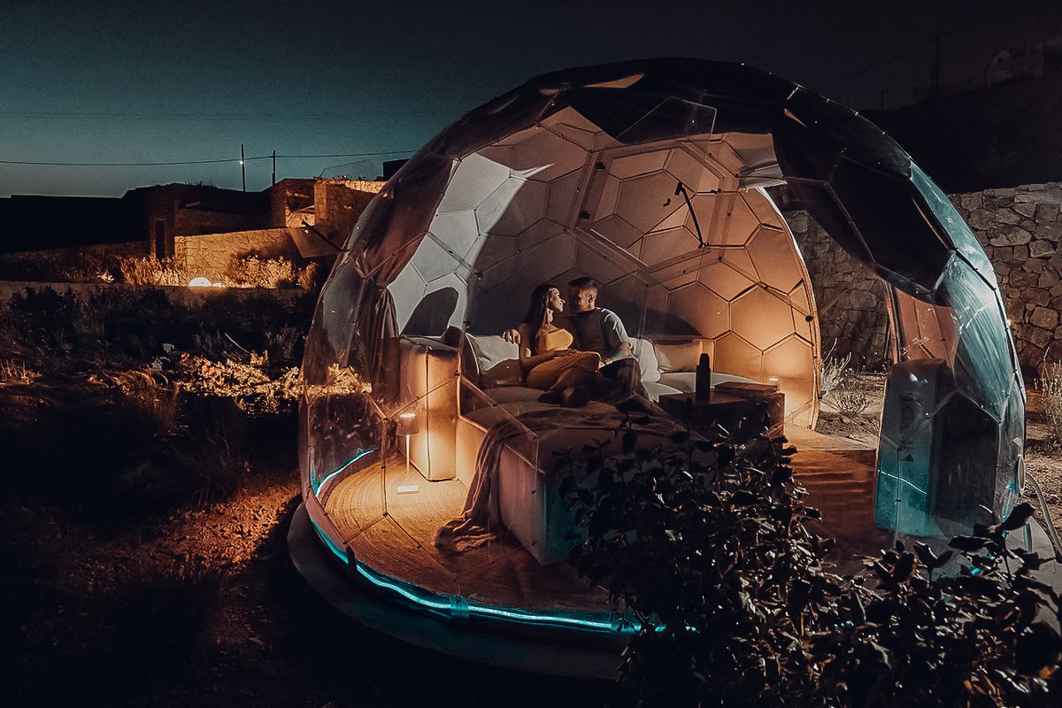 Couple in geodome romantic night with ambient lighting glamping experience