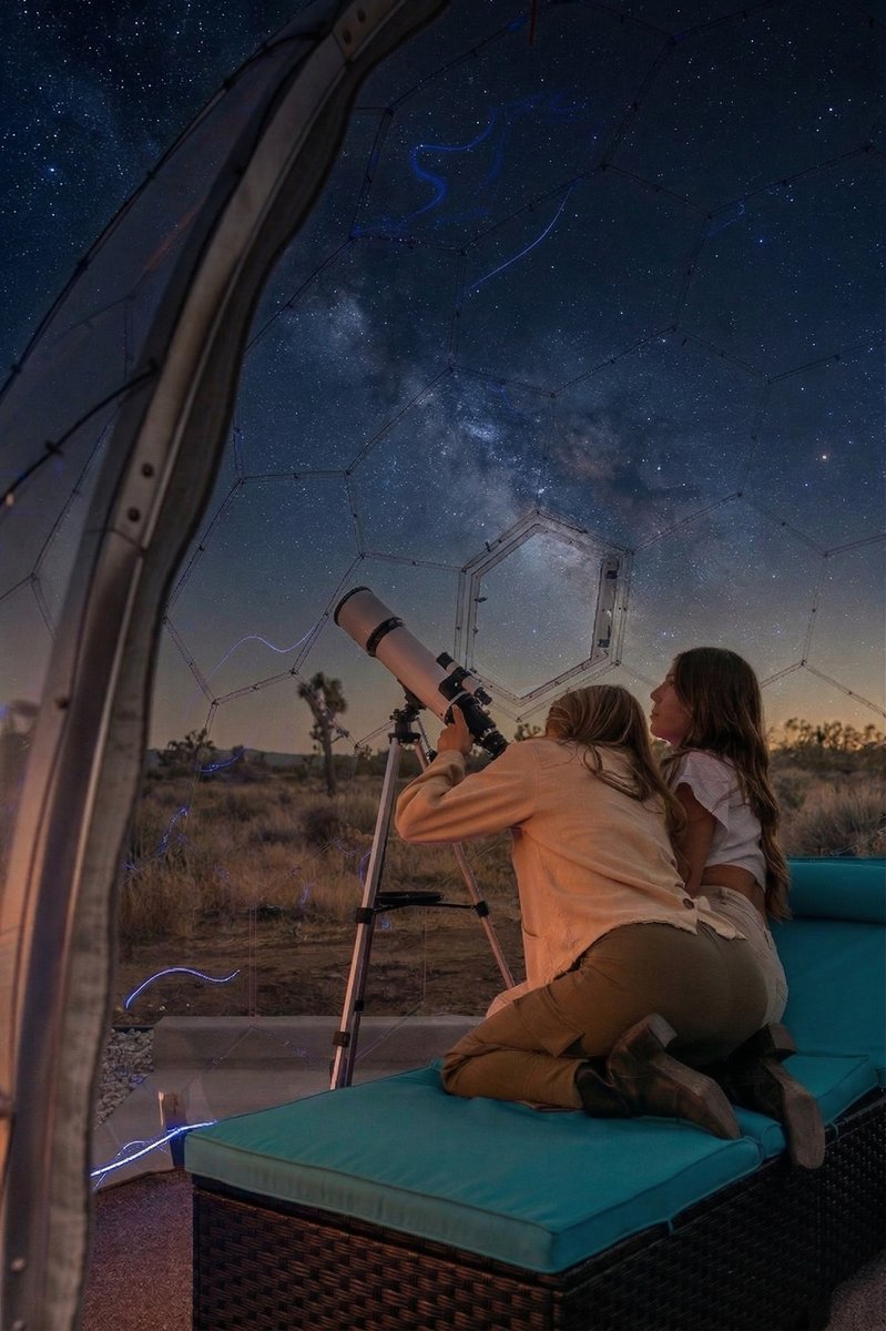 Stargazing through geodome with telescope under milky way night sky