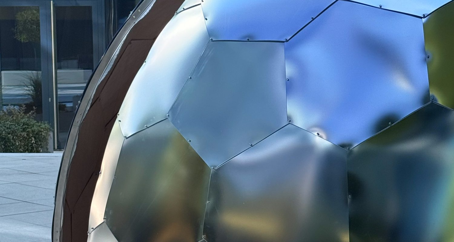Close-up of a Hypedome satin-mirror shell, its facets holding a soft reflection of the sky
