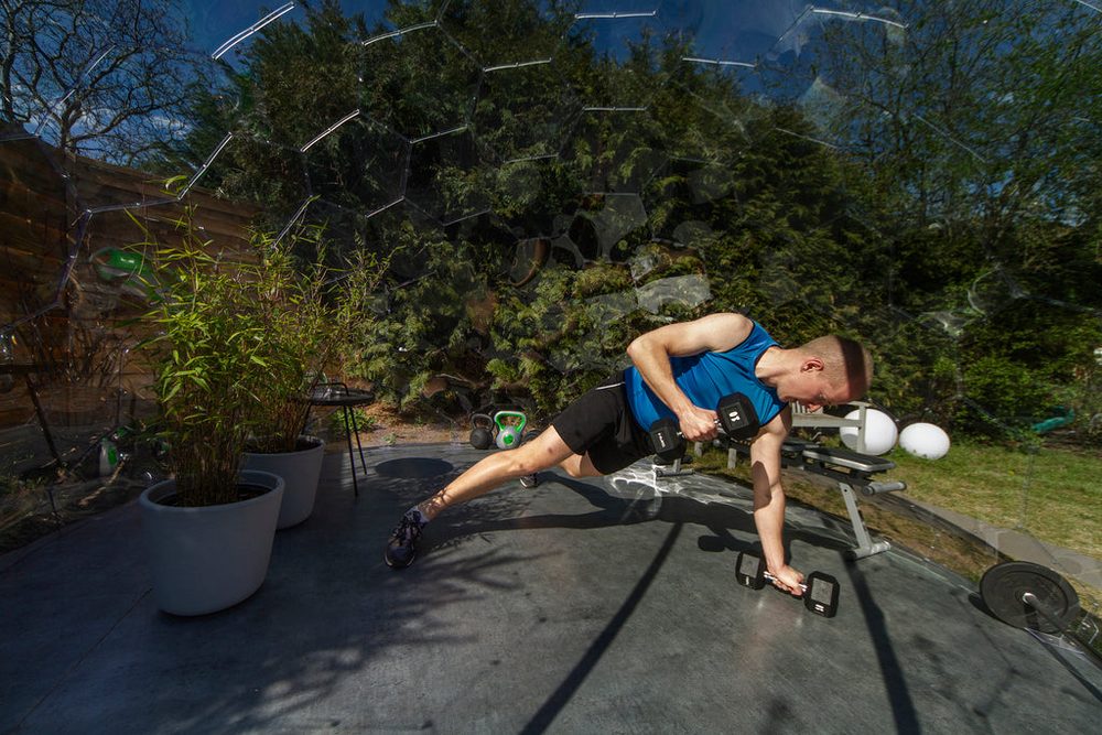 A person doing light strength training with equipment inside a garden gym Wellness Dome