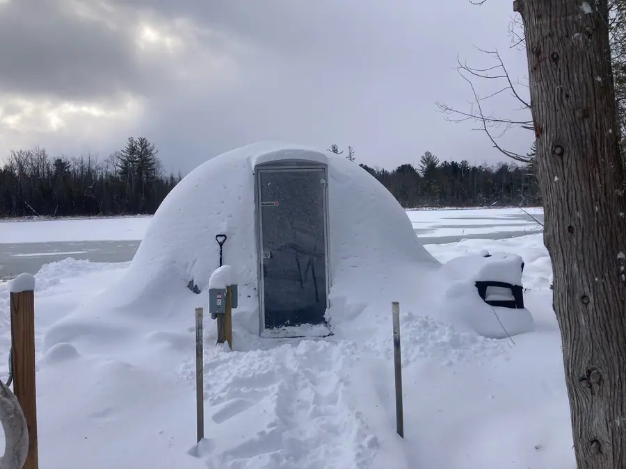 Hypedome almost fully buried by snowfall beside a frozen lake