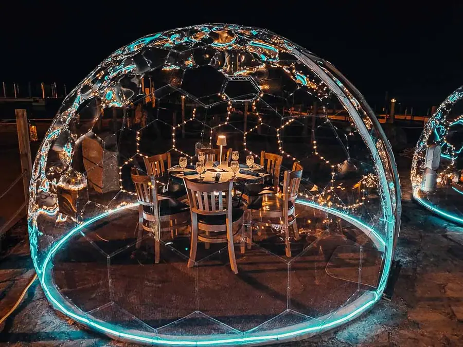Clear dining dome with teal LED ring and fairy lights around a set table