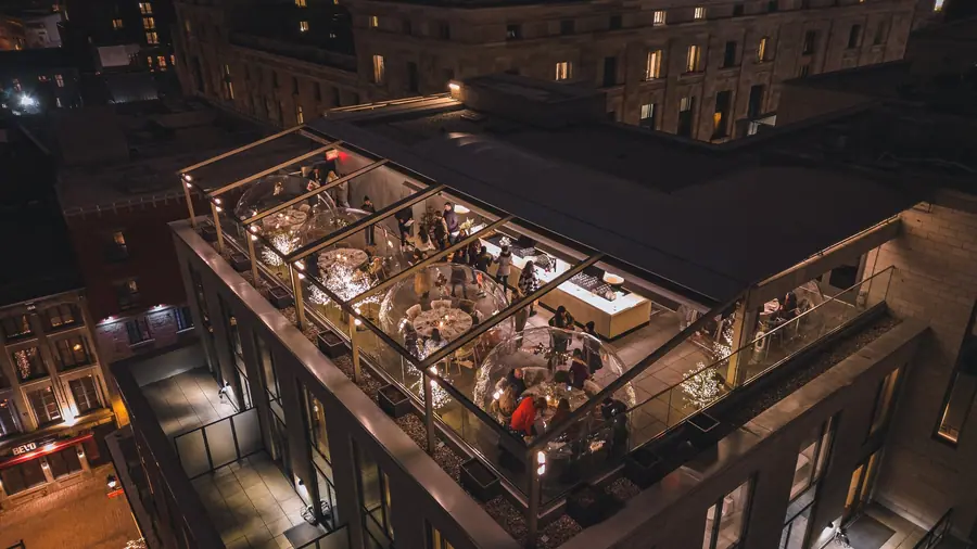 Aerial night view of a rooftop restaurant terrace with illuminated dining domes