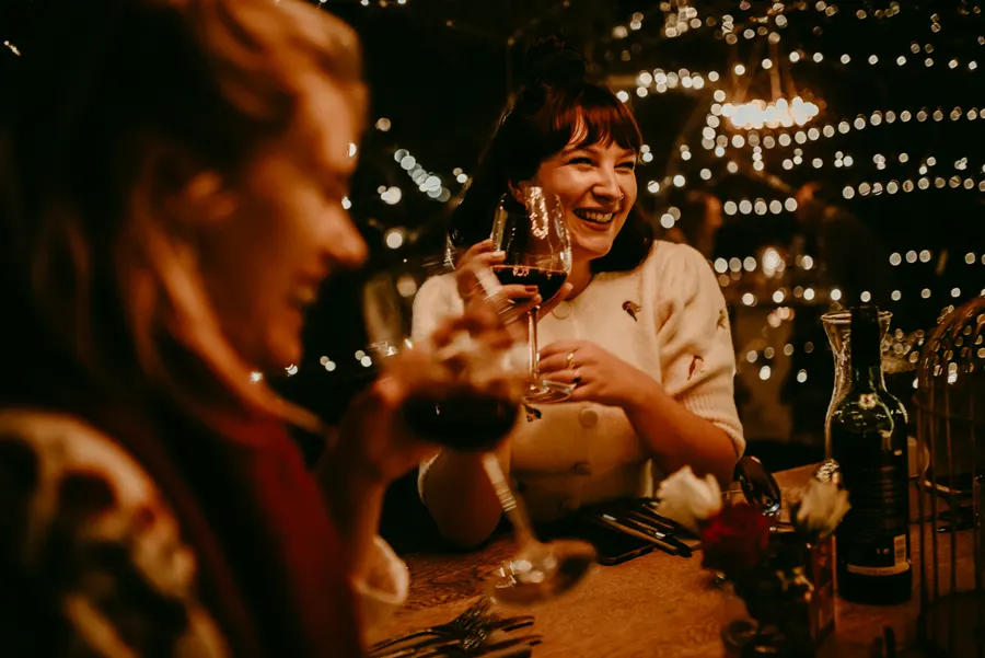 Two friends laughing and toasting with red wine inside a dome at The Willow Tree