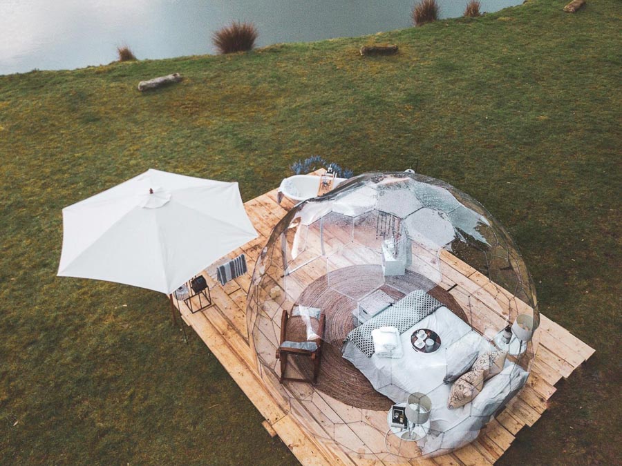 Dôme de glamping transparent avec lit au bord du lac