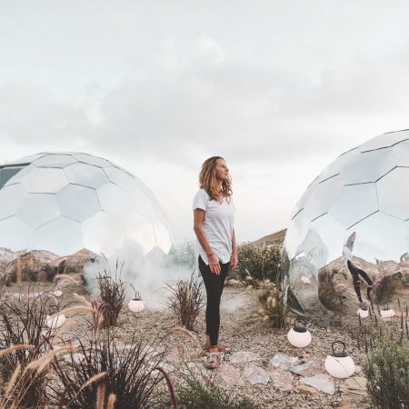 A woman standing between two glamping pods