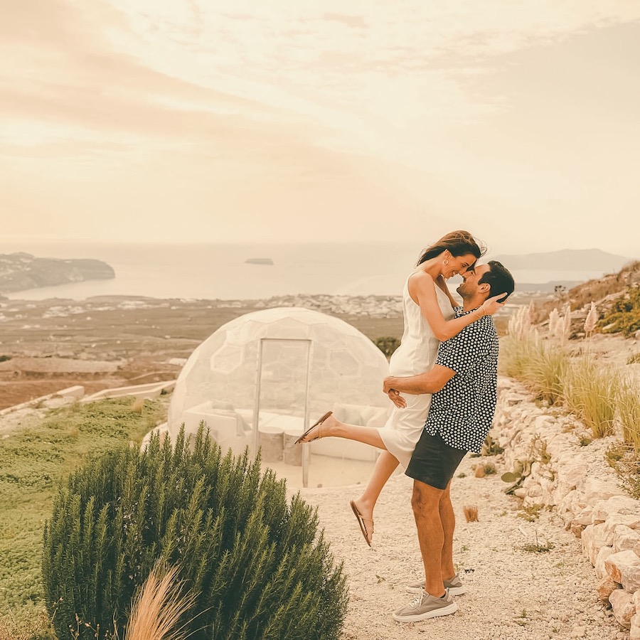 Un couple passant un bon moment ensemble, avec un dôme extérieur et la mer derrière eux.