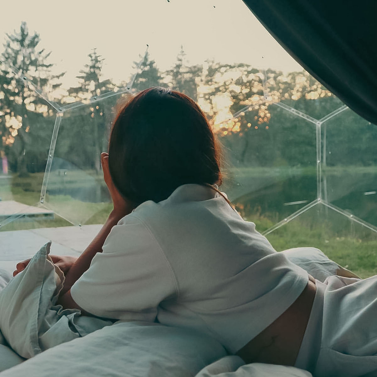 Frau beobachtet die Natur von der Hypedome-Glamping-Kapsel aus
