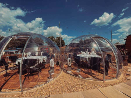 Two clear igloo domes ventilated with open doors and electric fans