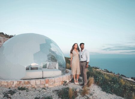 A couple standing in front of the glamping dome by the sea