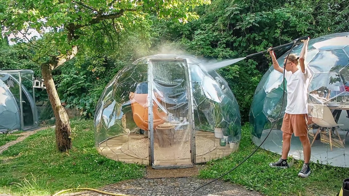 Un homme nettoie minutieusement un module de jardin Hypedome à l'aide d'un nettoyeur à haute pression.