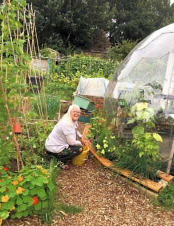 A lady gardening next to the geodesic greenhouse dome