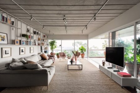 A modern living room with large windows and vast greenery