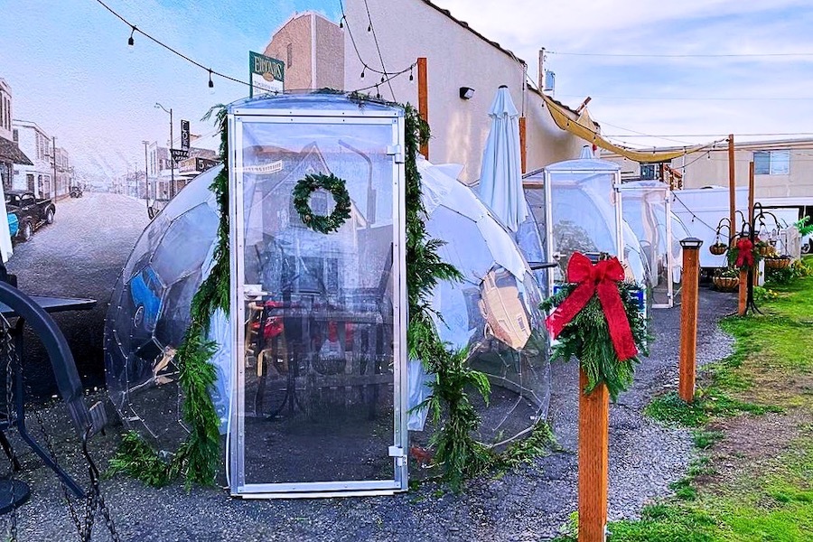 Les cabines à manger sont décorées dans un esprit de Noël, avec des couronnes, des branches de sapin, des rubans rouges et des cloches.