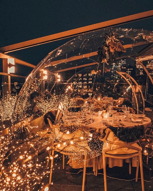 Dîner dans un restaurant sur le toit sous le ciel de minuit, éclairé par des lumières féeriques.
