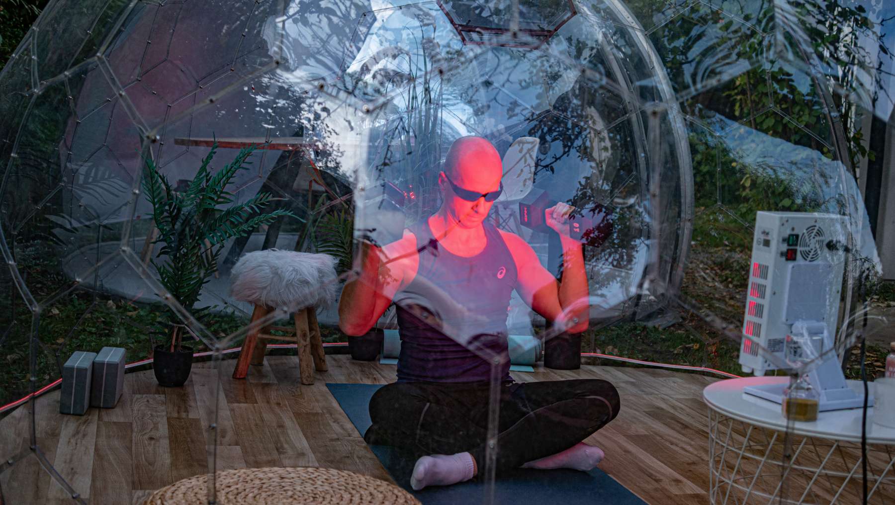 Ein Mann trainiert in einem Hypedome mit Rotlicht als Teil eines auf Langlebigkeit ausgerichteten Wellness-Retreats im Hinterhof