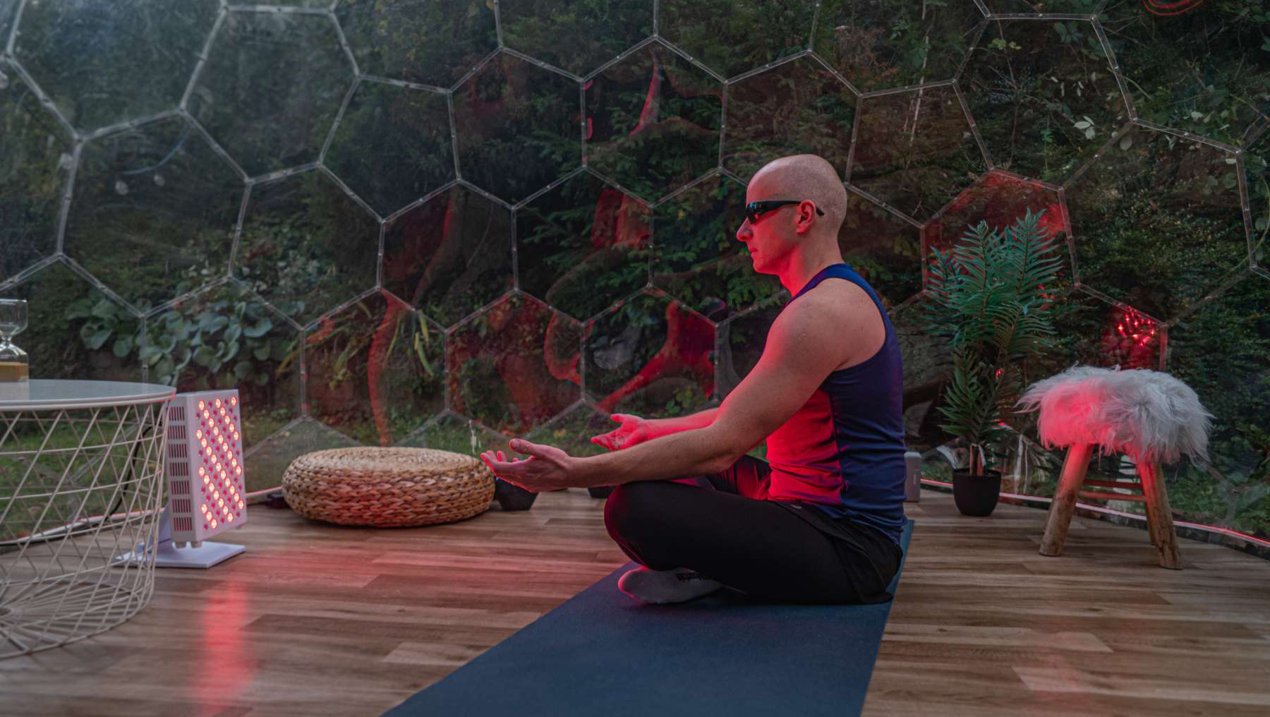 Ein Mann trainiert in einem Hypedome-Wellness-Raum mit Rotlicht für ein Wellness-Retreat im Hinterhof, das sich auf Langlebigkeit konzentriert