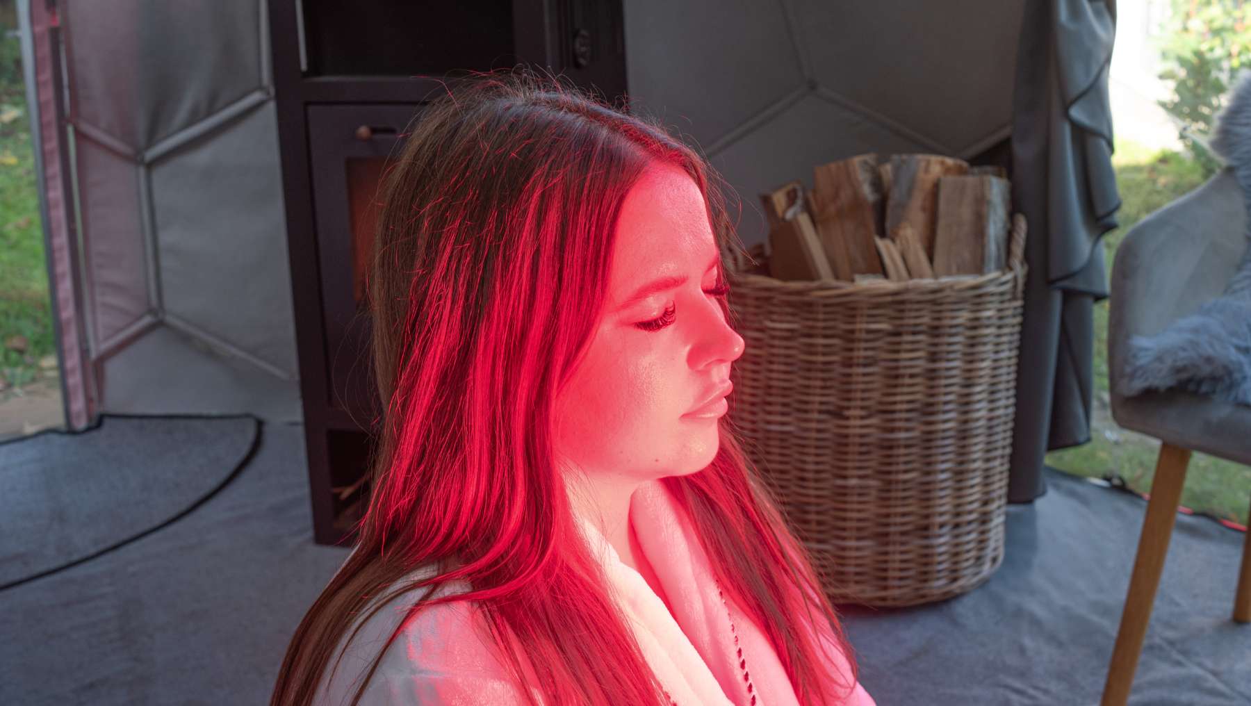 Eine Frau entspannt sich in einem Hypedome während einer Rotlichtsitzung als Teil eines auf Langlebigkeit ausgerichteten Wellness-Retreats im Hinterhof