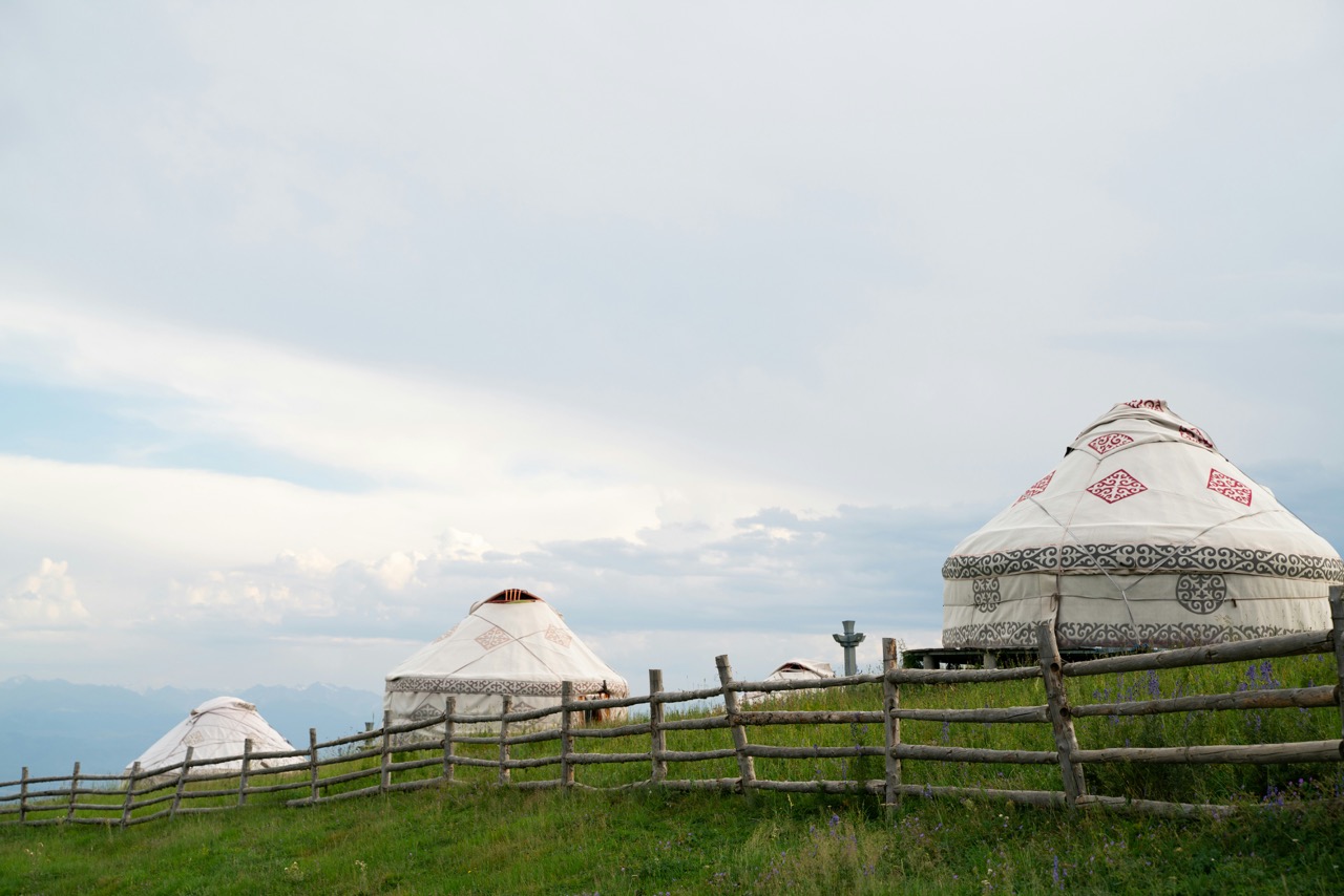 Yourtes traditionnelles sur une colline herbeuse sous un ciel d'été