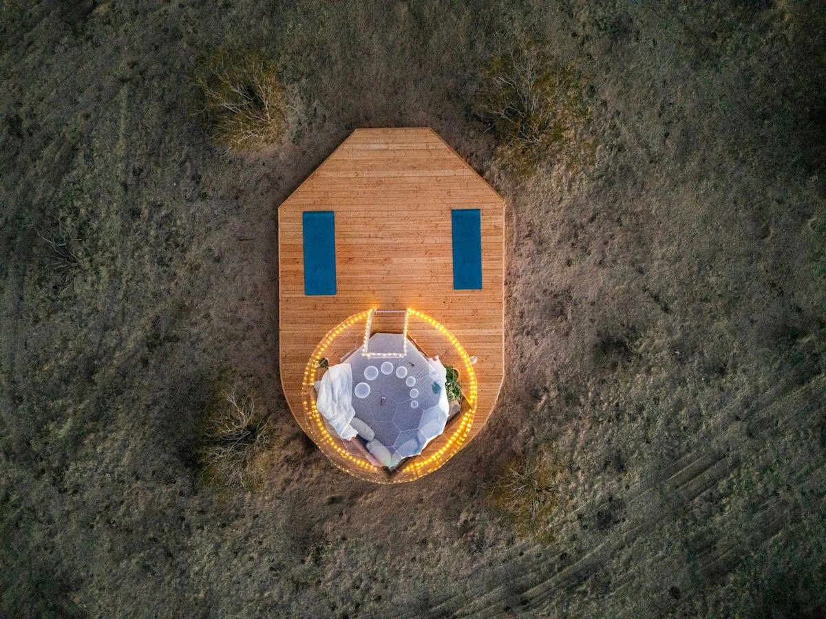 Luftaufnahme der geodätischen Kuppel Airbnb in der Abenddämmerung mit Lichterketten auf dem Holzdeck - hochkonvertierendes Heldenbild