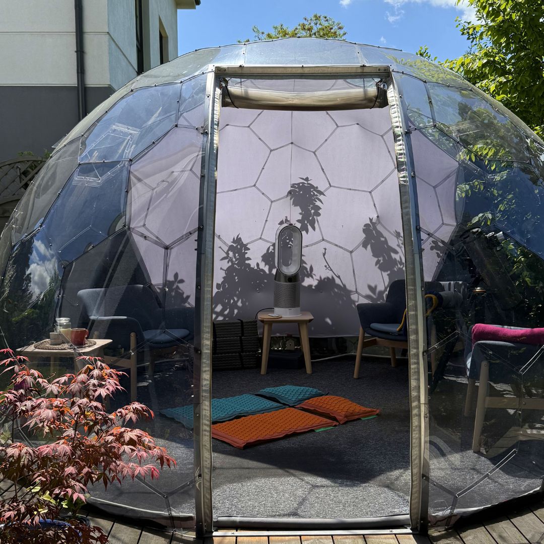 Primo piano di un tappetino per agopressione Pranamat ECO arancione, con un Hypedome visibile nel giardino retrostante