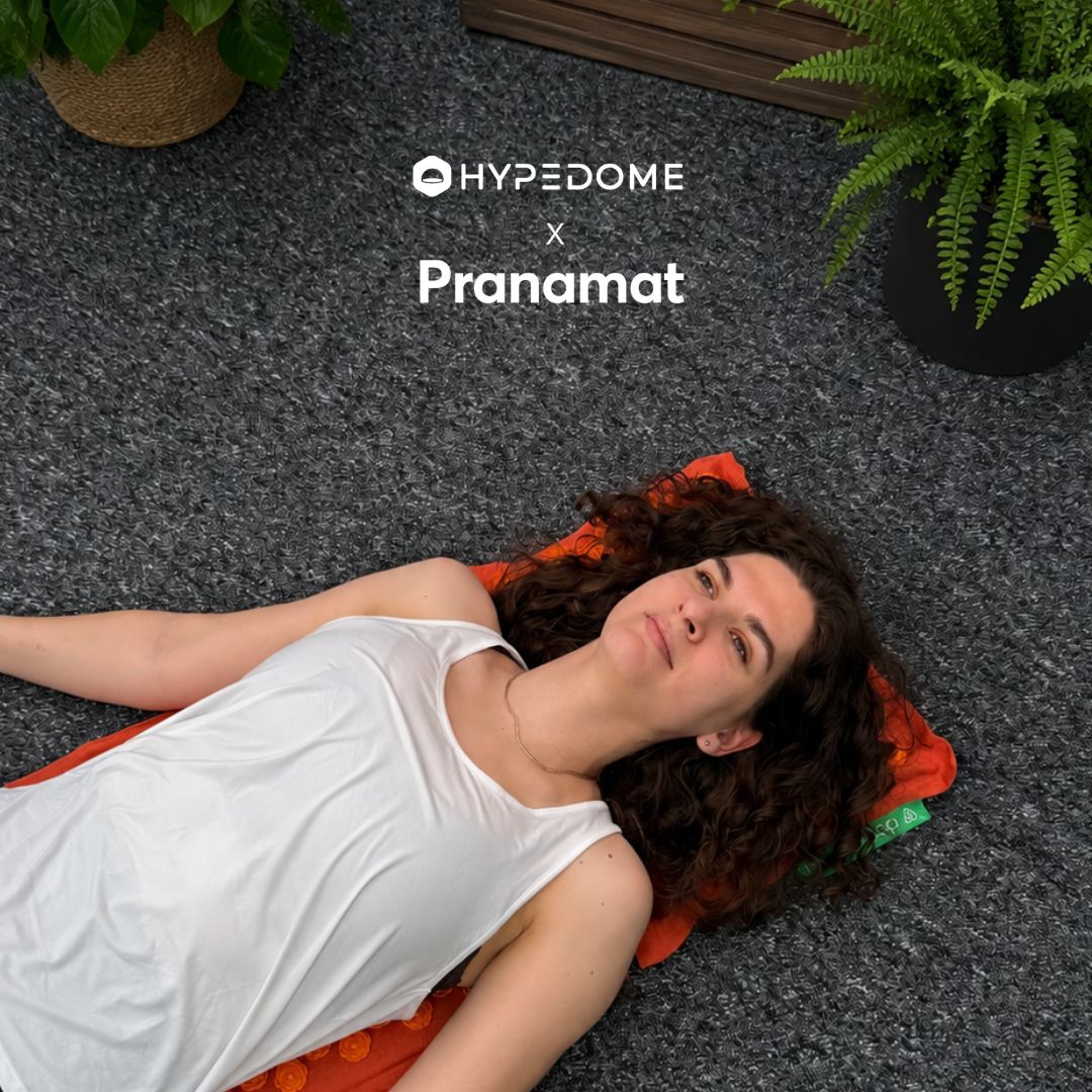 Una persona distesa su un tappetino per agopressione Pranamat arancione — Hypedome x Pranamat