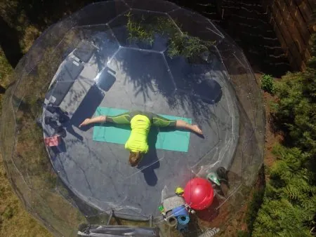 A stretched lady practising yoga in a garden gym dome