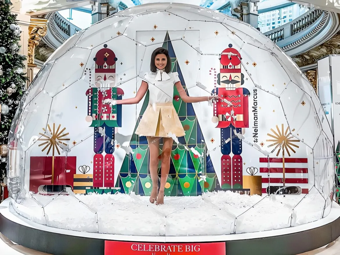 A giant snow globe with Christmas decorations and a young woman inside