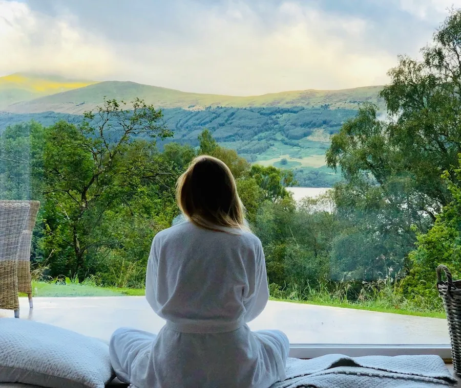 A woman enhancing well-being and admiring the nature behind the window