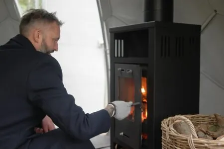 A man adding wood to a wood burning stove