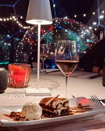 A glass of wine and dessert on the table in a dining dome