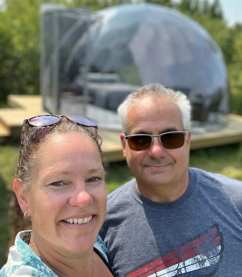 Janice and her husband in front of their off-grid dome
