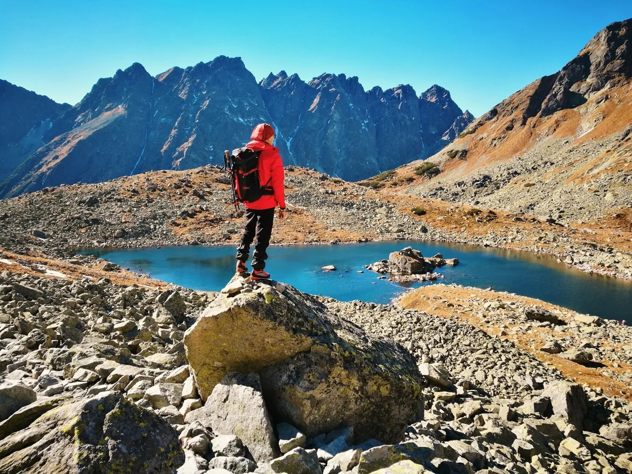 A man standing on the rock, watching the lake