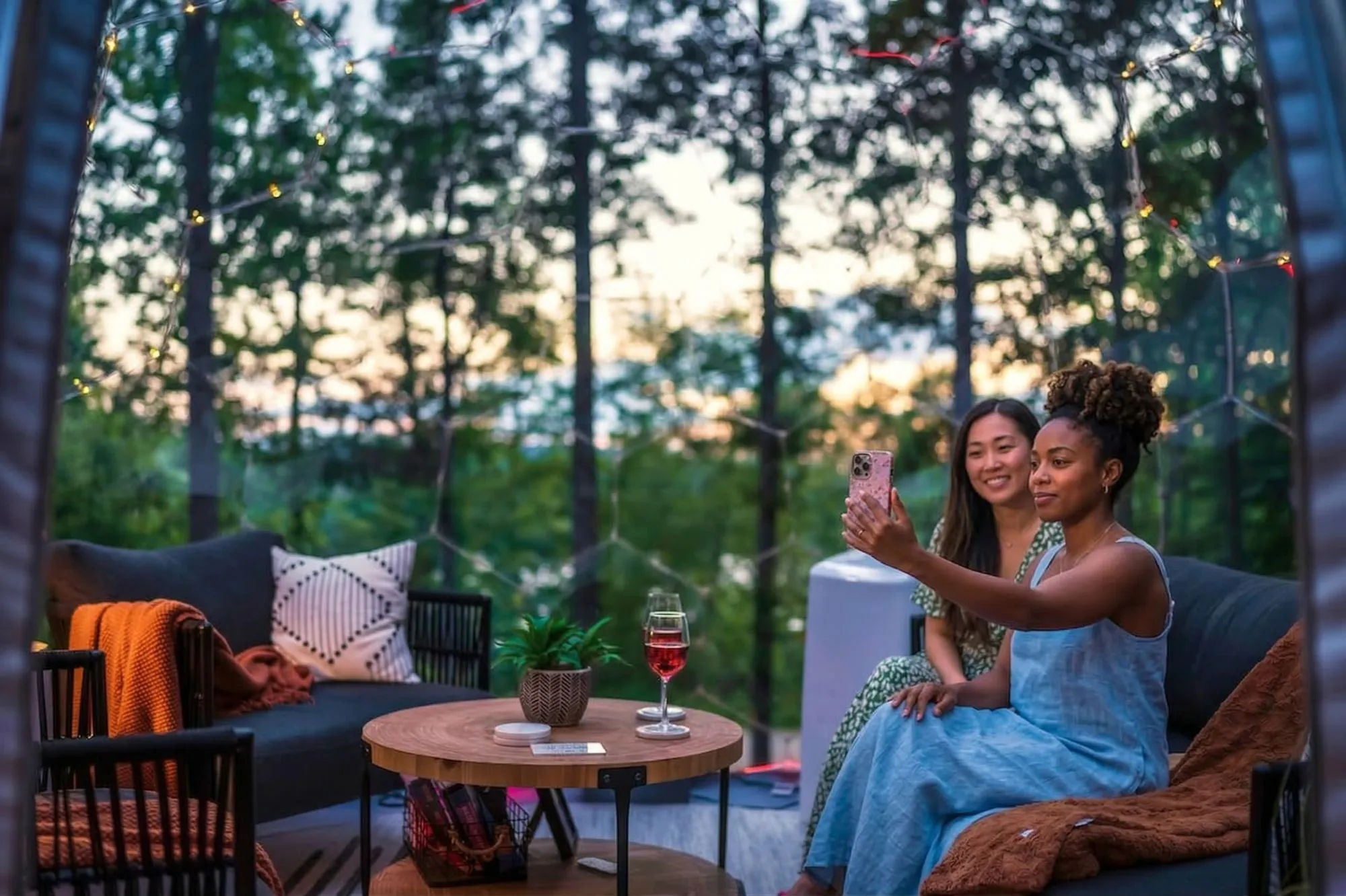 Lifestyle frame: friends gathered around a dome at sunset — the kind of inhabited shot Airbnb guests respond to